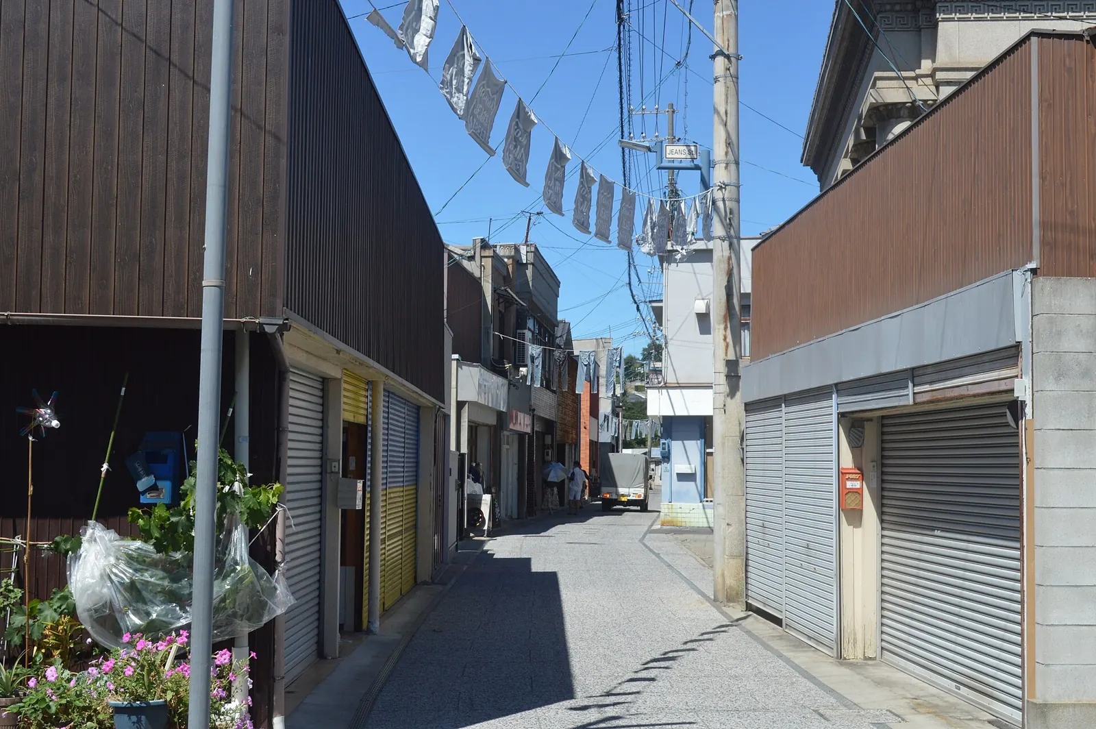 A narrow street in Kojima, Japan, with jeans hanging on lines above the road