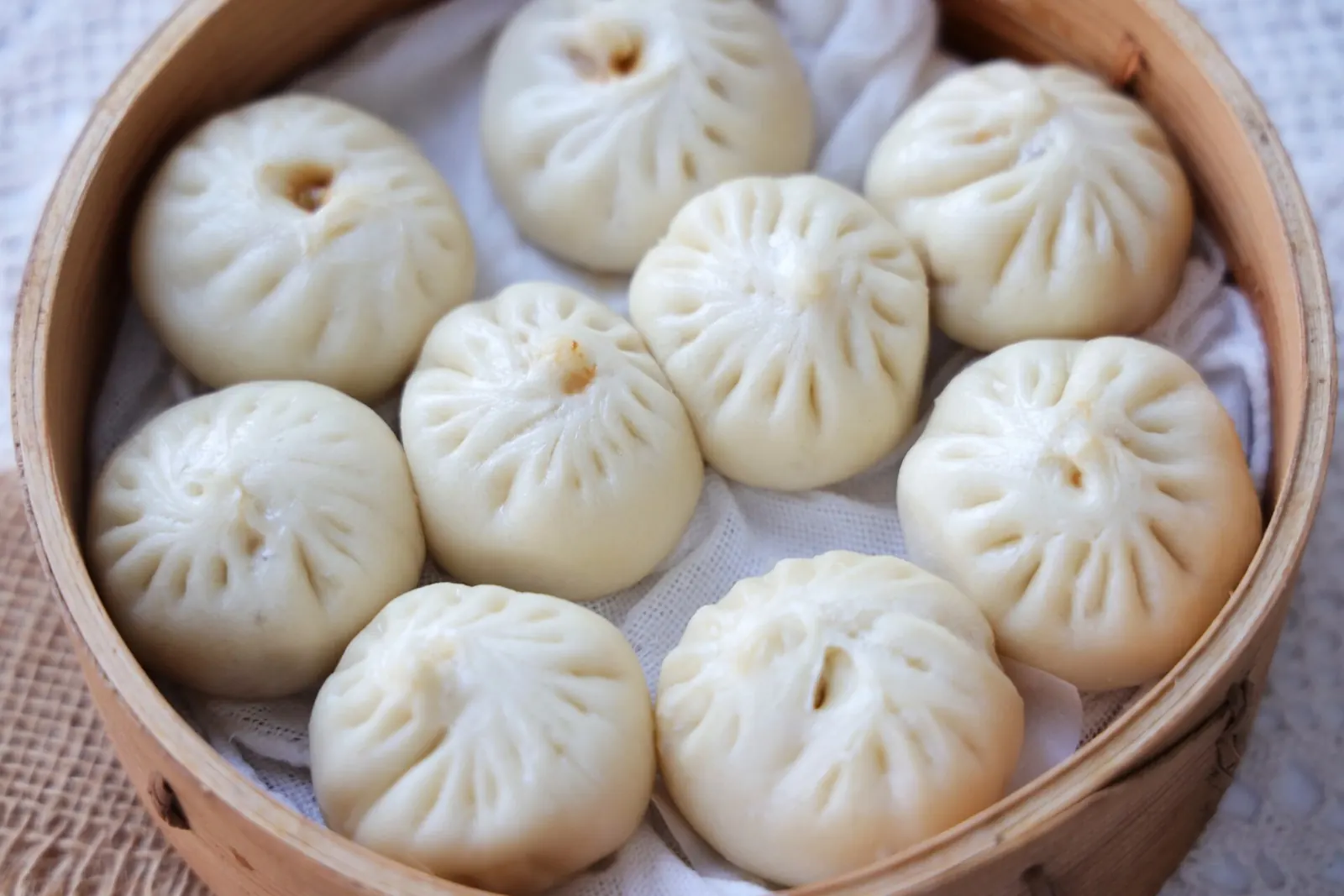 A bamboo steamer filled with pleated xiaolongbao soup dumplings