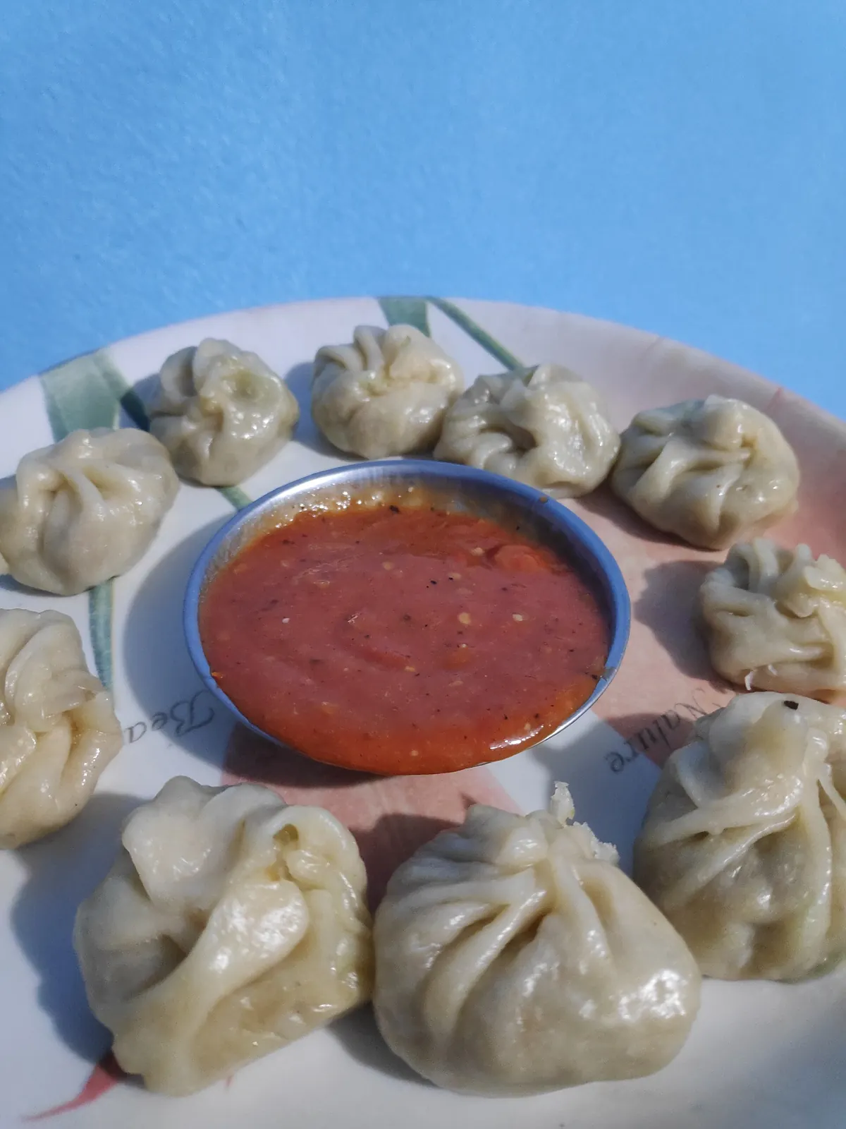 Nepali vegetable momos around a bowl of red tomato achar