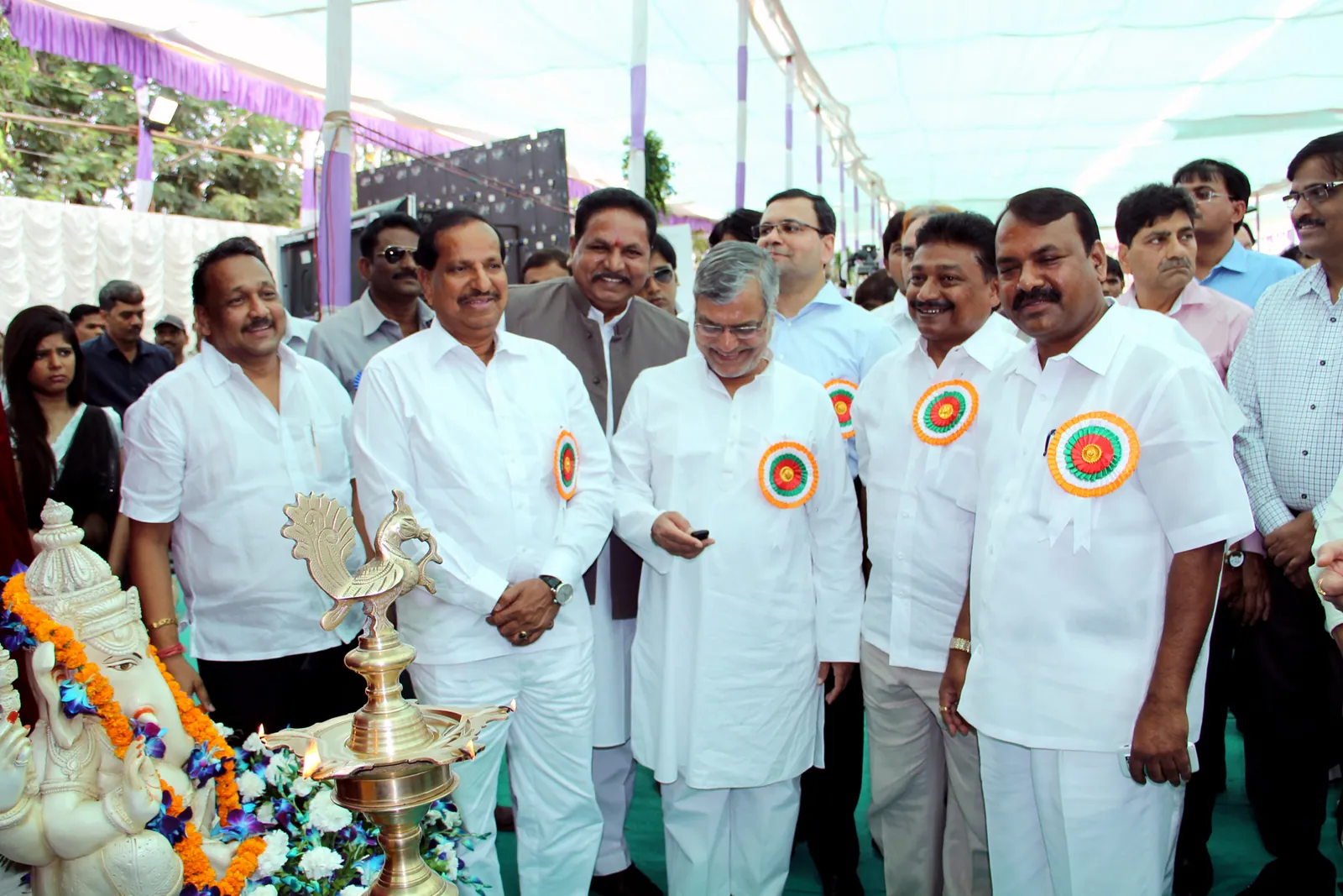Union Road Transport Minister C. P. Joshi in a white kurta pressing a remote button, flanked by officials wearing rosettes, beside a brass lamp and a Ganesha idol at a launch ceremony under a tent