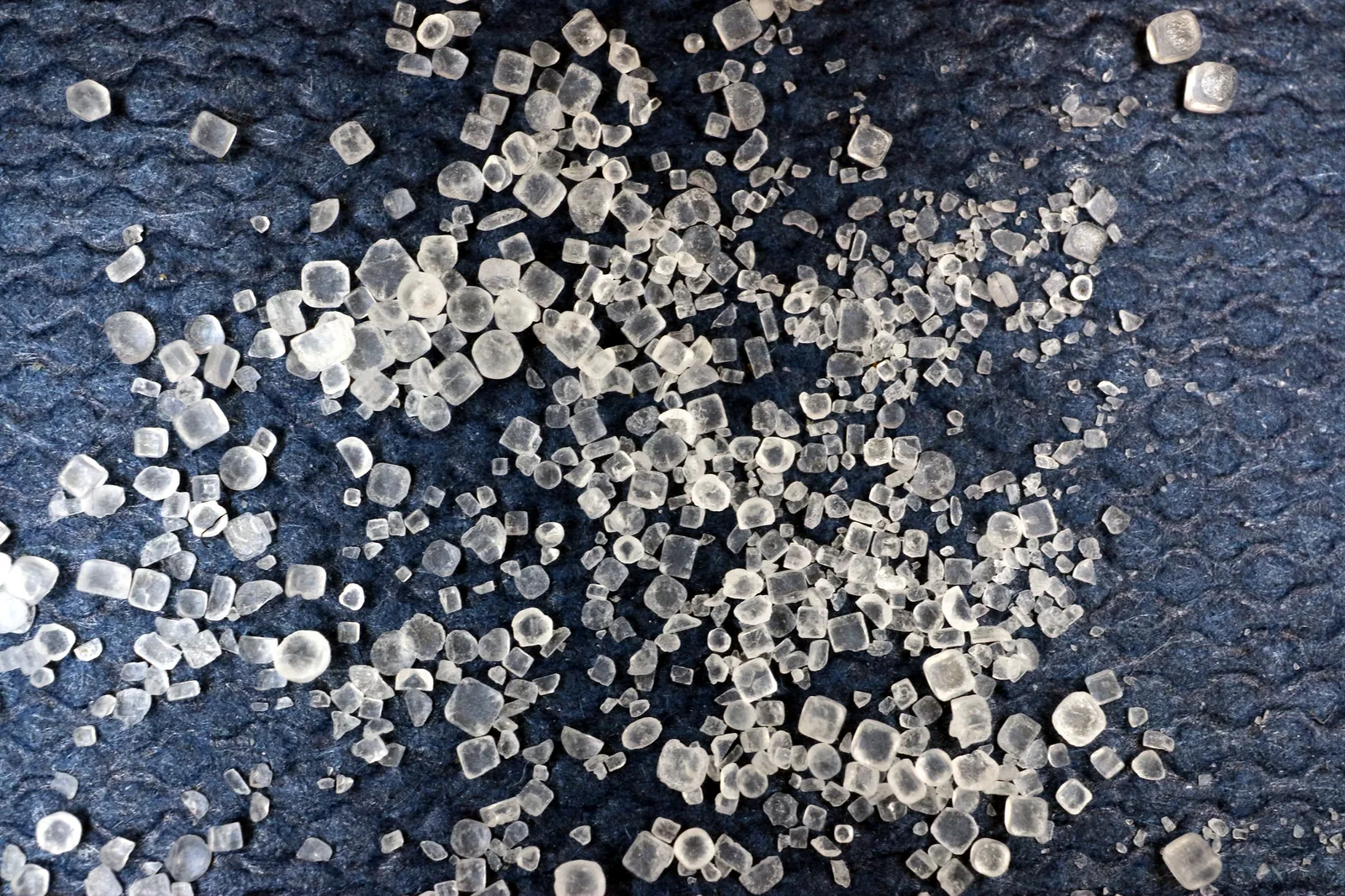 Macro photograph of white table salt crystals on a dark background