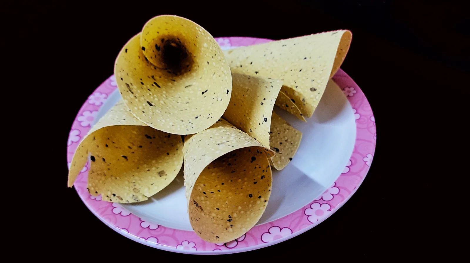 Golden roasted papad with blistered surface on a plain background