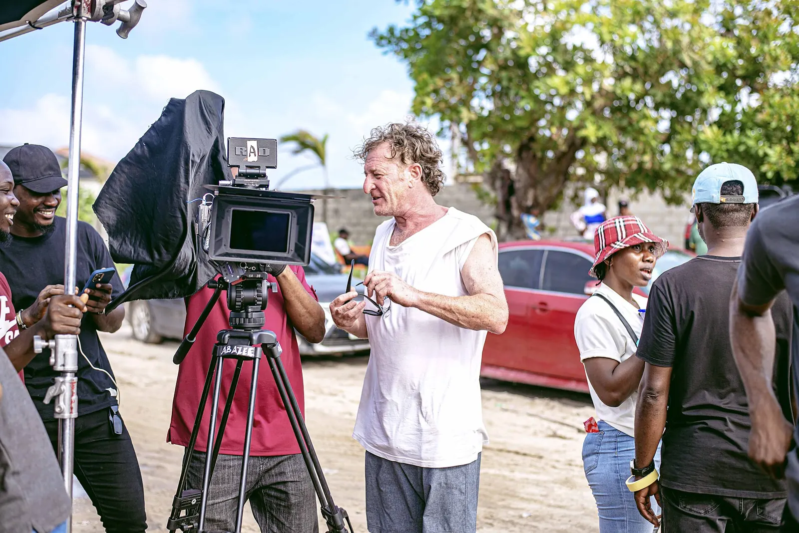 A camera operator and crew filming a scene on a Nollywood set