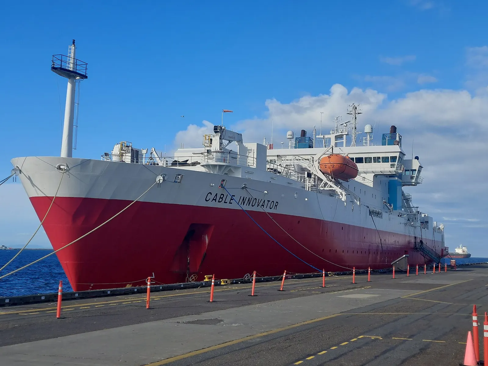 The red-hulled cable ship CS Cable Innovator moored at port