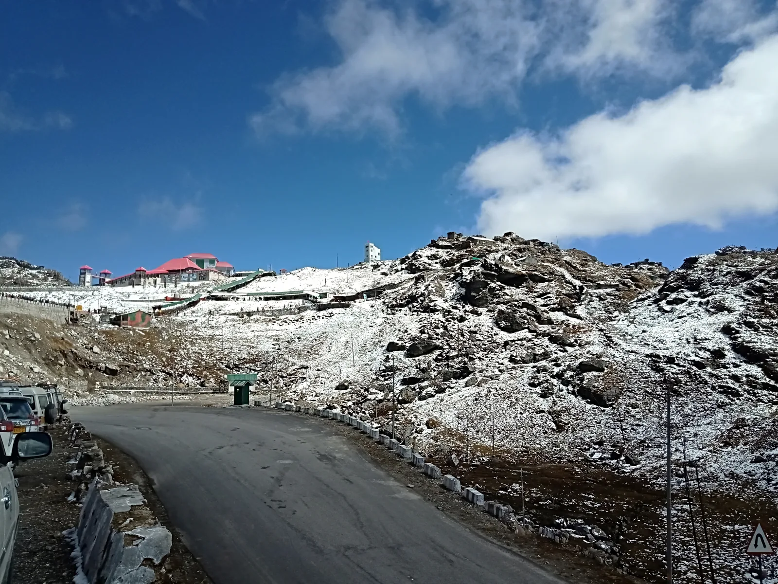 Mountain road and ridgeline at Nathu La pass in Sikkim in October, with bare slopes and a partly cloudy sky