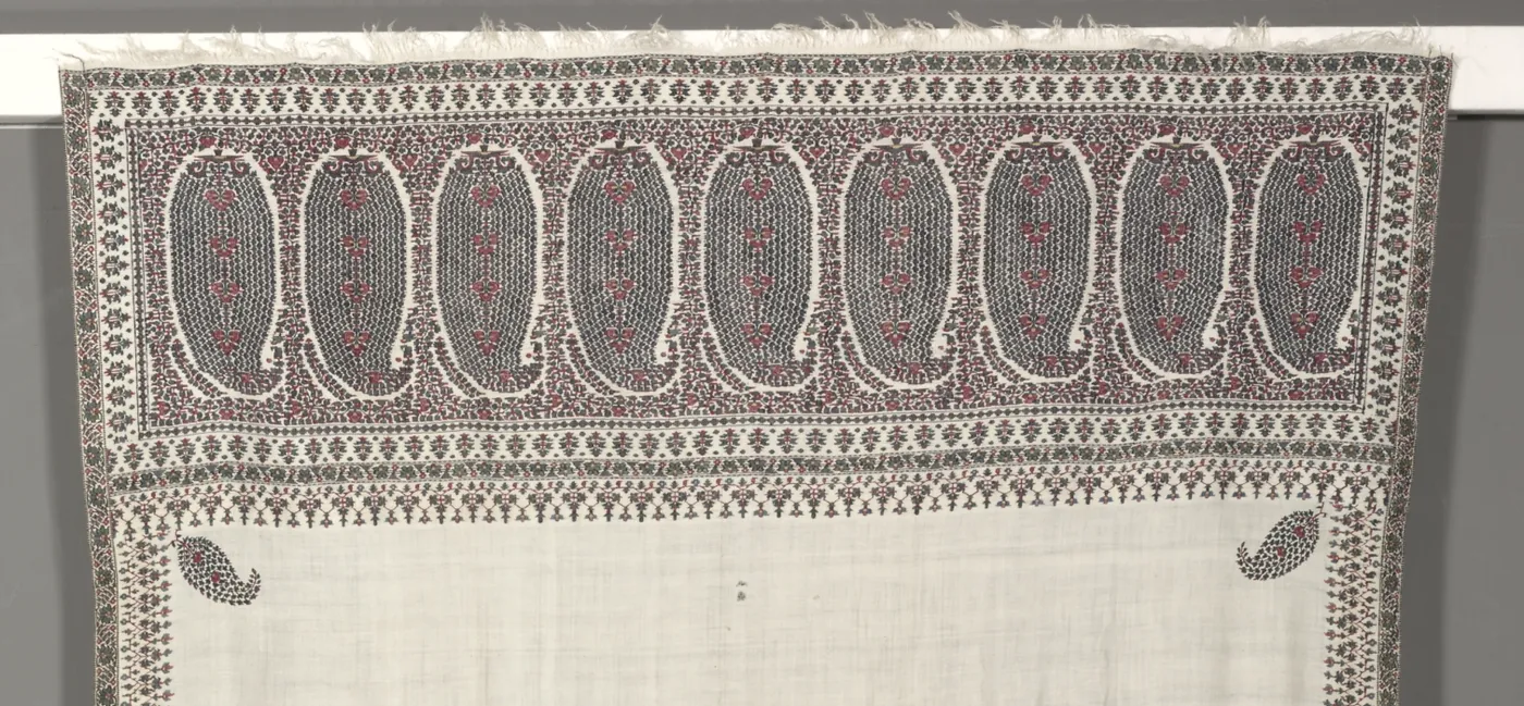End border of a cream 19th-century Kashmir shawl with a row of nine large dark teardrop buta motifs and a single small buta in each corner of the plain field
