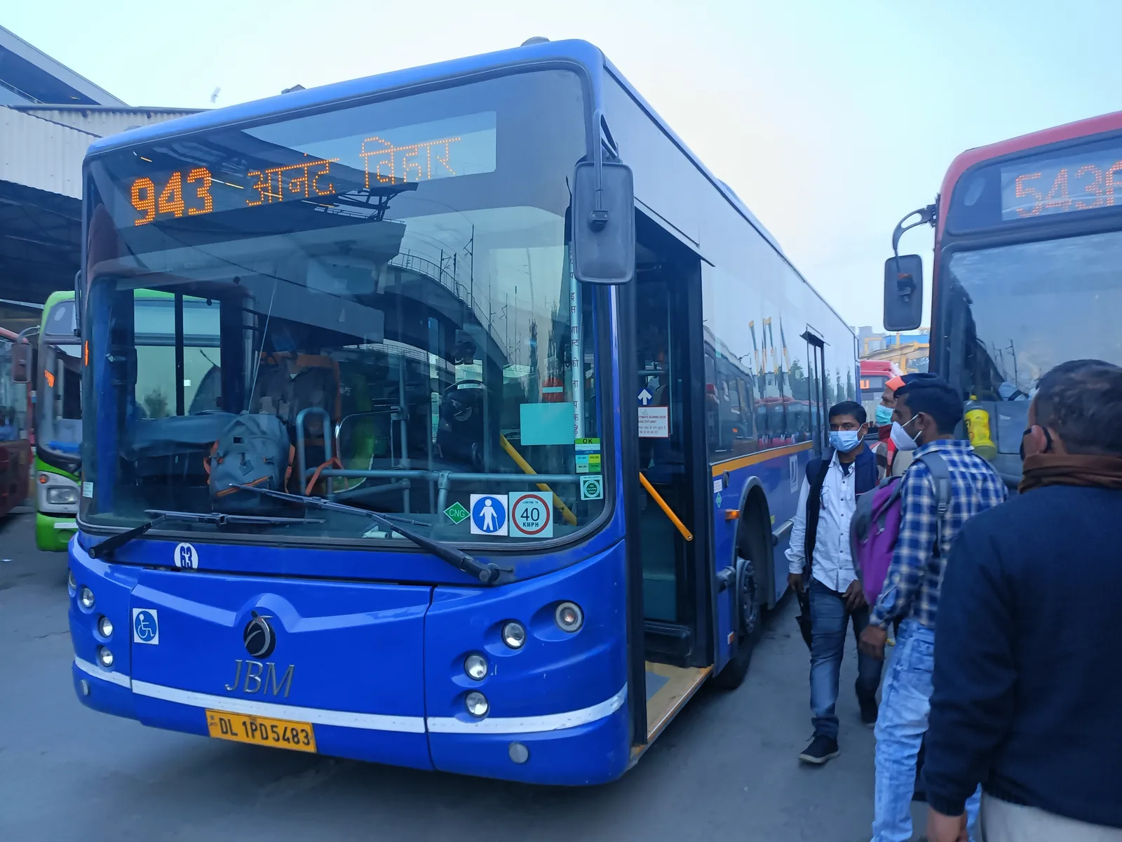 A green and orange JBM CityLife CNG air-conditioned cluster bus at Anand Vihar ISBT in Delhi