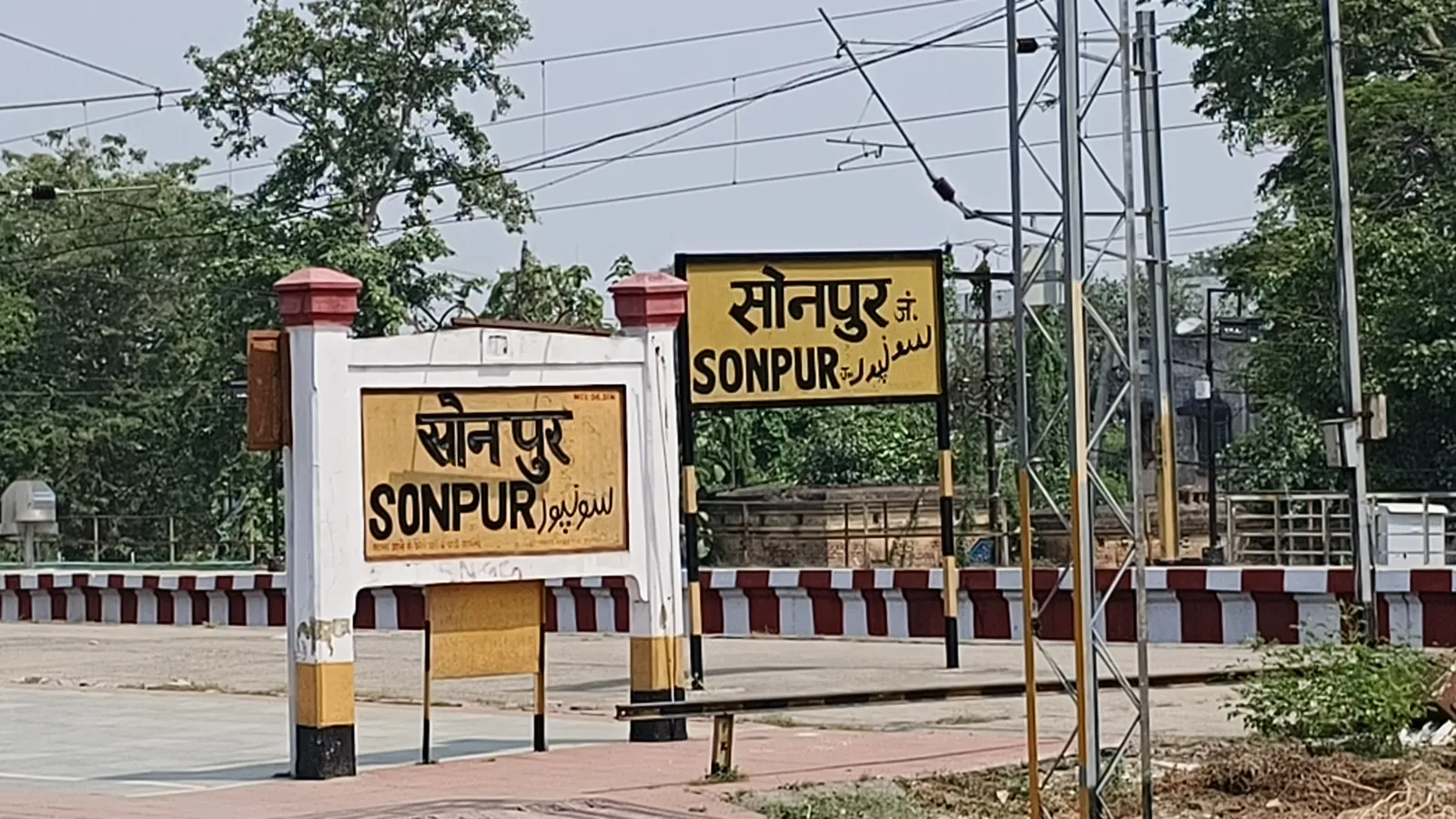Yellow railway station nameboards at Sonpur in Bihar showing the station name in Hindi Devanagari, English Latin letters and Urdu script