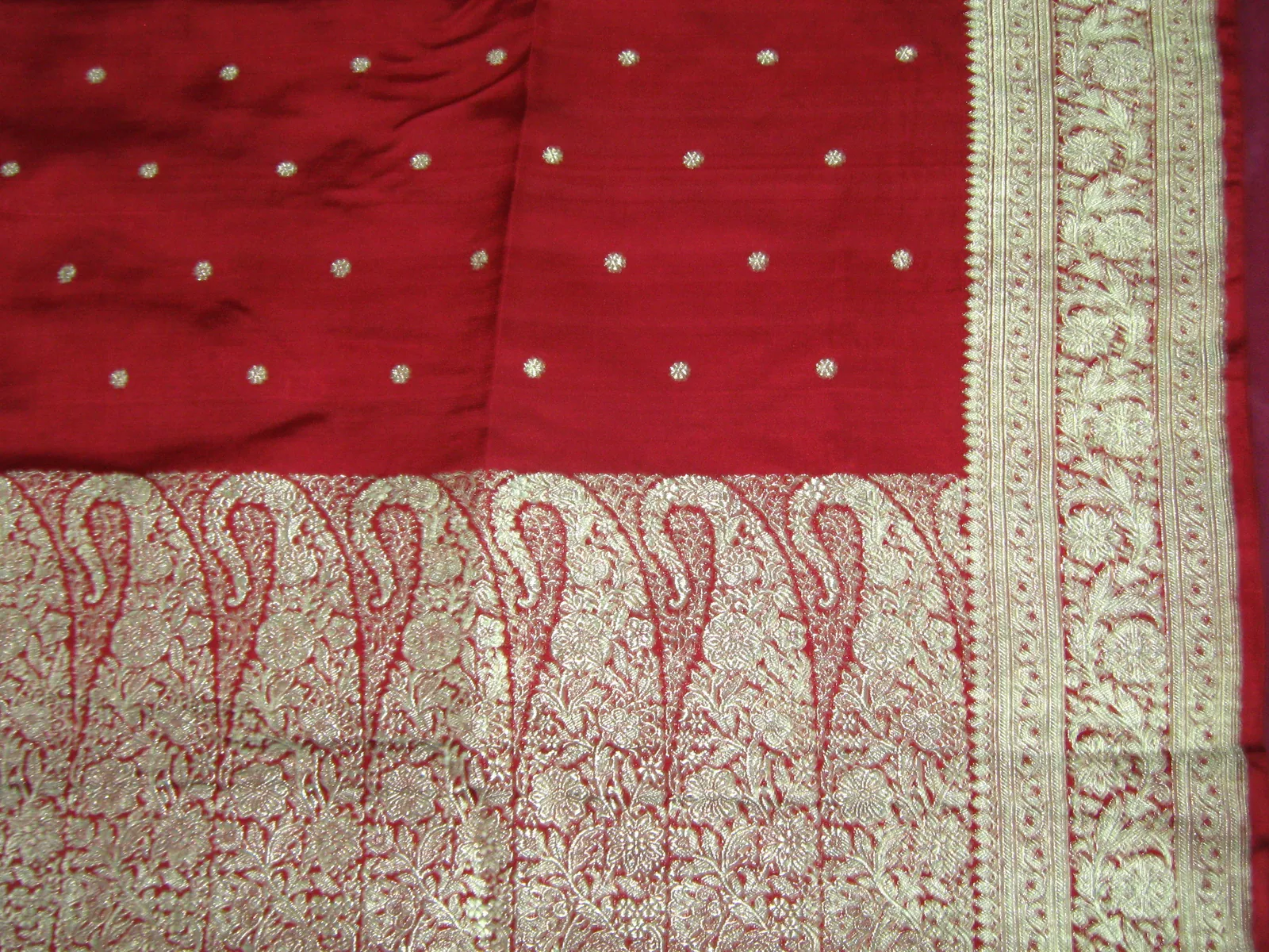 Close view of a Banarasi silk saree pallu with dense gold zari floral brocade on deep red silk