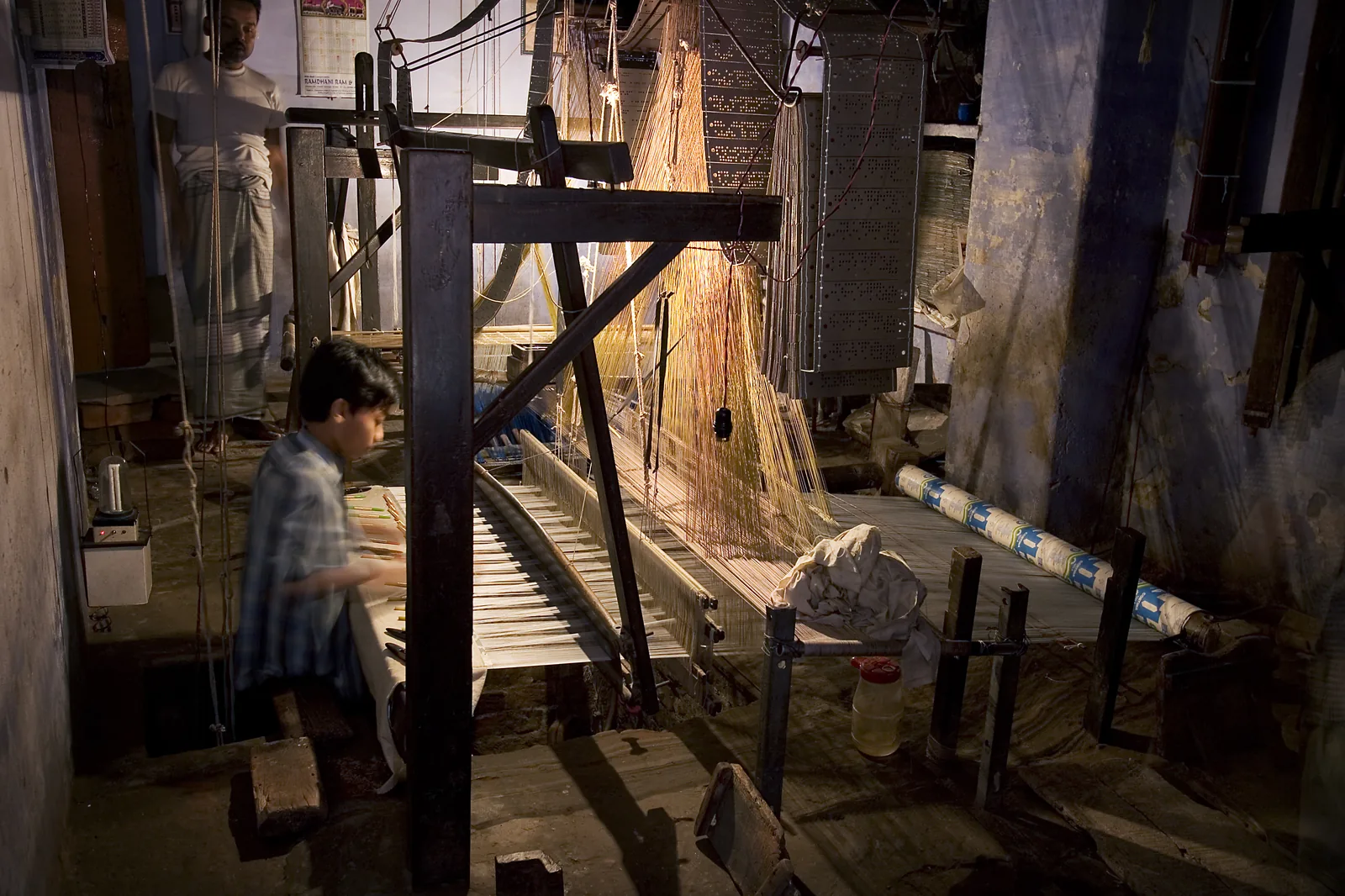 Wooden handloom in Varanasi with silk warp threads and Jacquard pattern harness above the weaving area