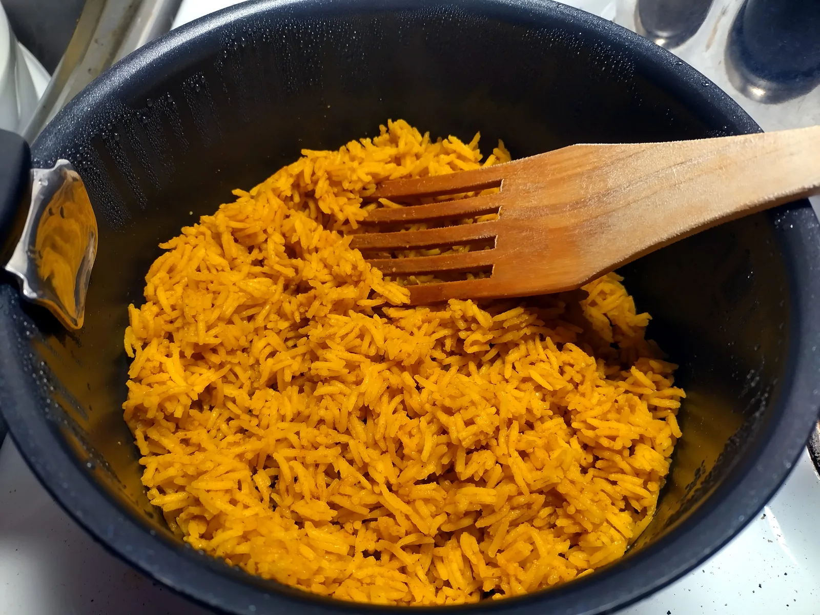 Fluffed cooked basmati rice in a metal pot, with separate long white grains after absorption cooking