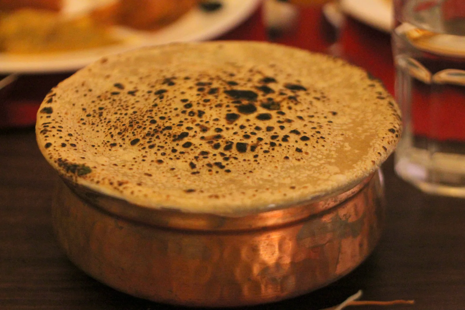 A copper pot of kacchi dum biryani sealed with a ring of flour dough, ready for slow cooking