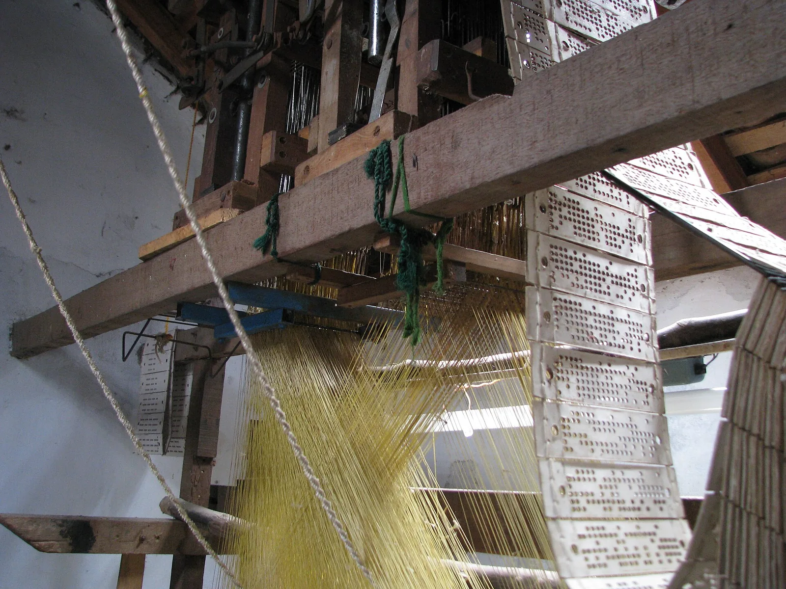 Close view of a complex handloom in Kanchipuram with pulley strings and pattern cards set up for weaving silk saris
