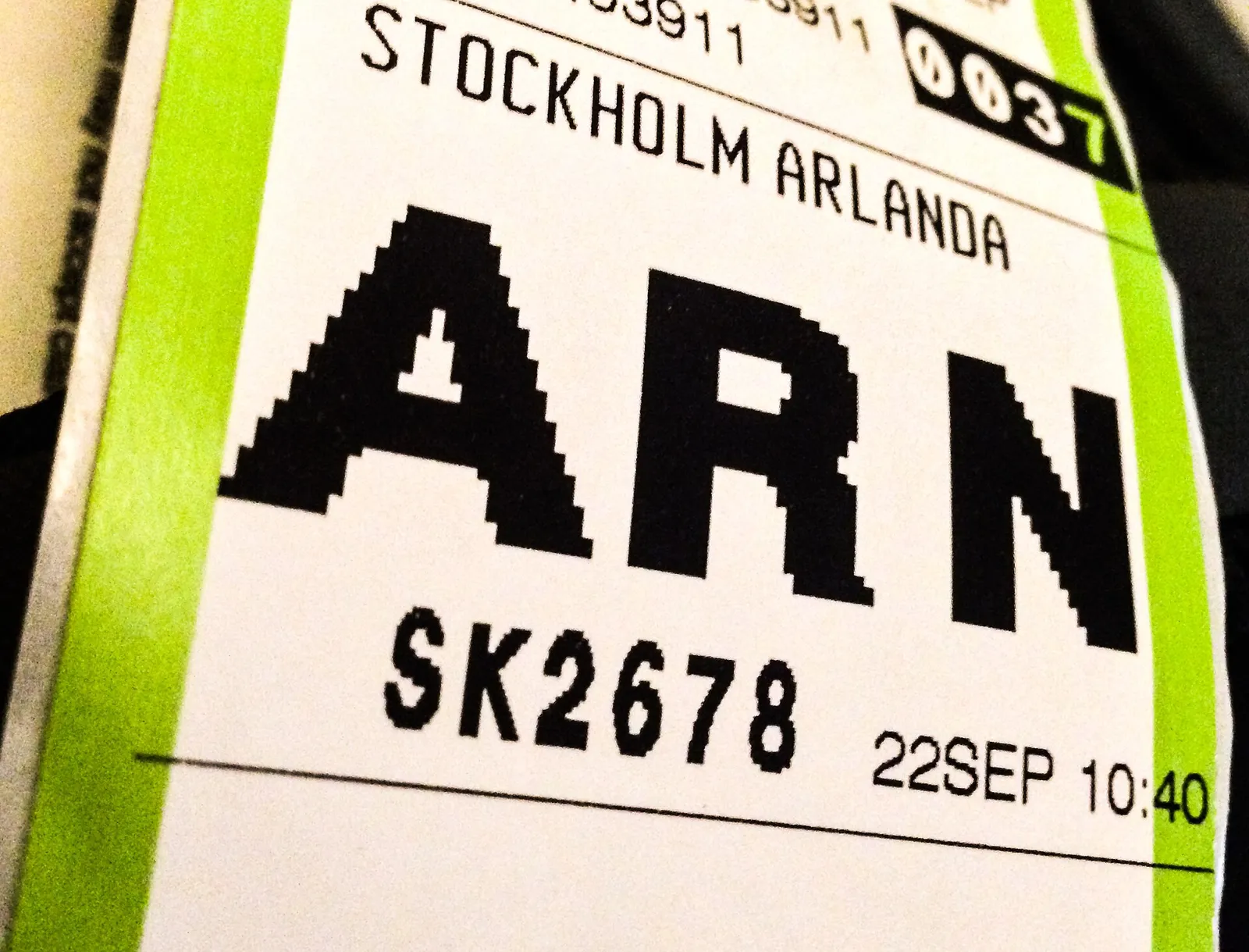 Close-up of a green and white airline baggage tag printed with the large airport code ARN for Stockholm Arlanda