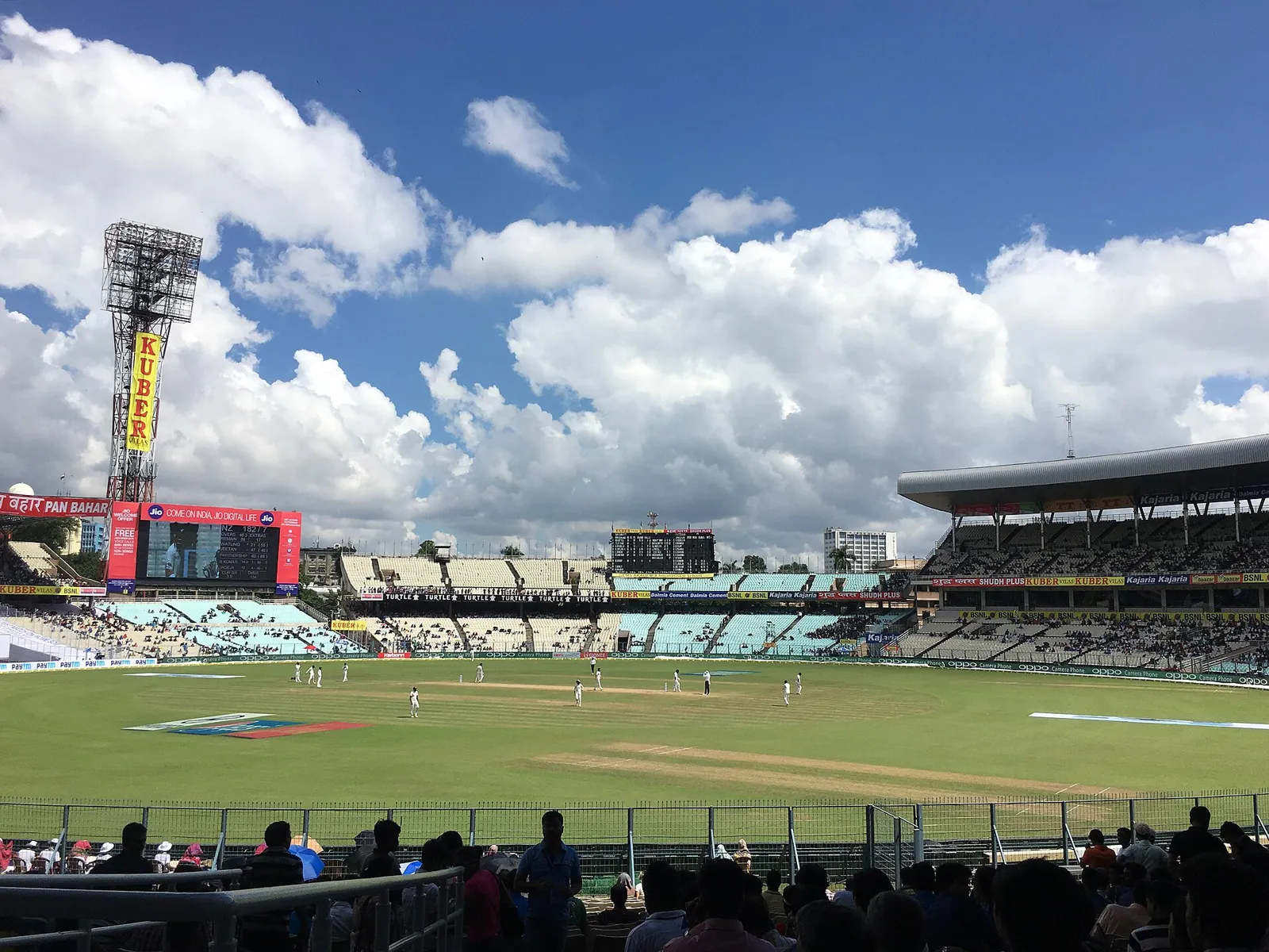View across the stands at Eden Gardens in Kolkata during a Test match, with the green outfield and the pale pitch in the middle under a blue sky