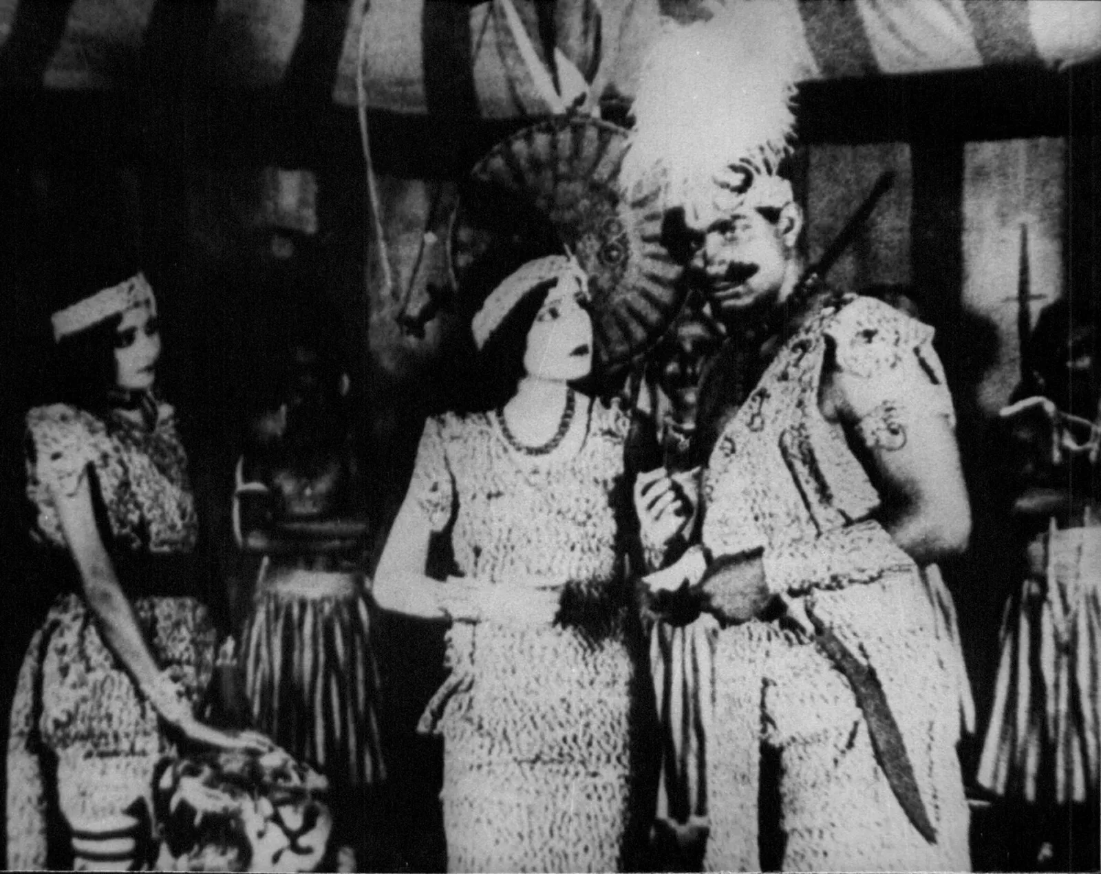 Black and white scene from the 1931 film Alam Ara showing three costumed performers standing together on a set