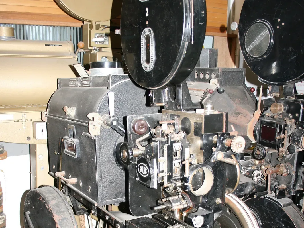 A black 1930s Gaumont Kalee 35mm cinema projector with its film spool housing and gate mechanism