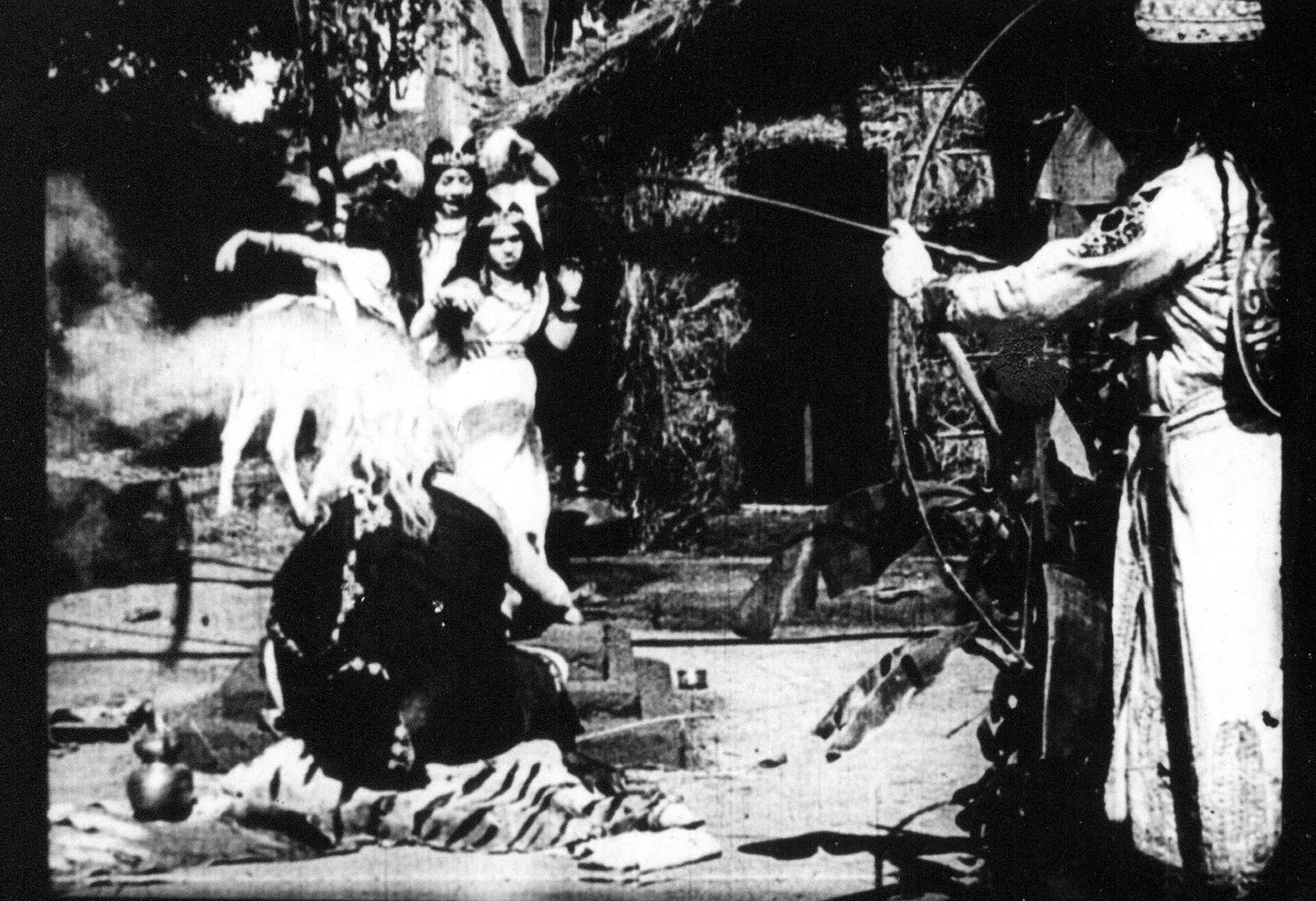 Black and white still from the 1913 silent film Raja Harishchandra showing costumed actors in an outdoor forest scene