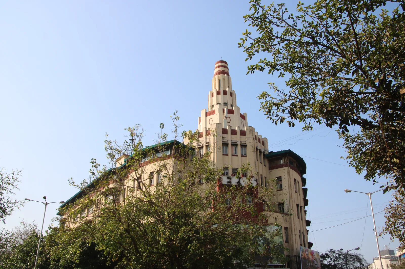 The cream Art Deco facade of Eros Cinema in Churchgate, Mumbai, with curved lettering above the entrance and traffic in the foreground