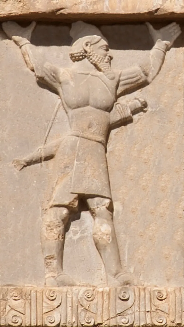 Stone relief of a bearded soldier from Hindush in a short tunic with a sword at his side, both arms raised to support the platform of a royal throne, carved on a cliff tomb