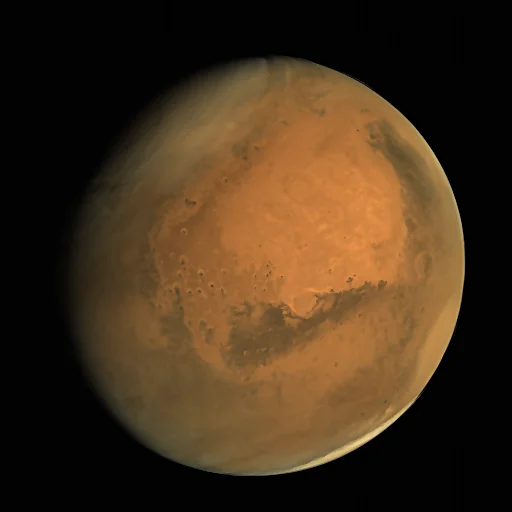 Full disc of Mars glowing orange against black space, with darker surface markings and pale haze along its edge, photographed by India's Mangalyaan orbiter
