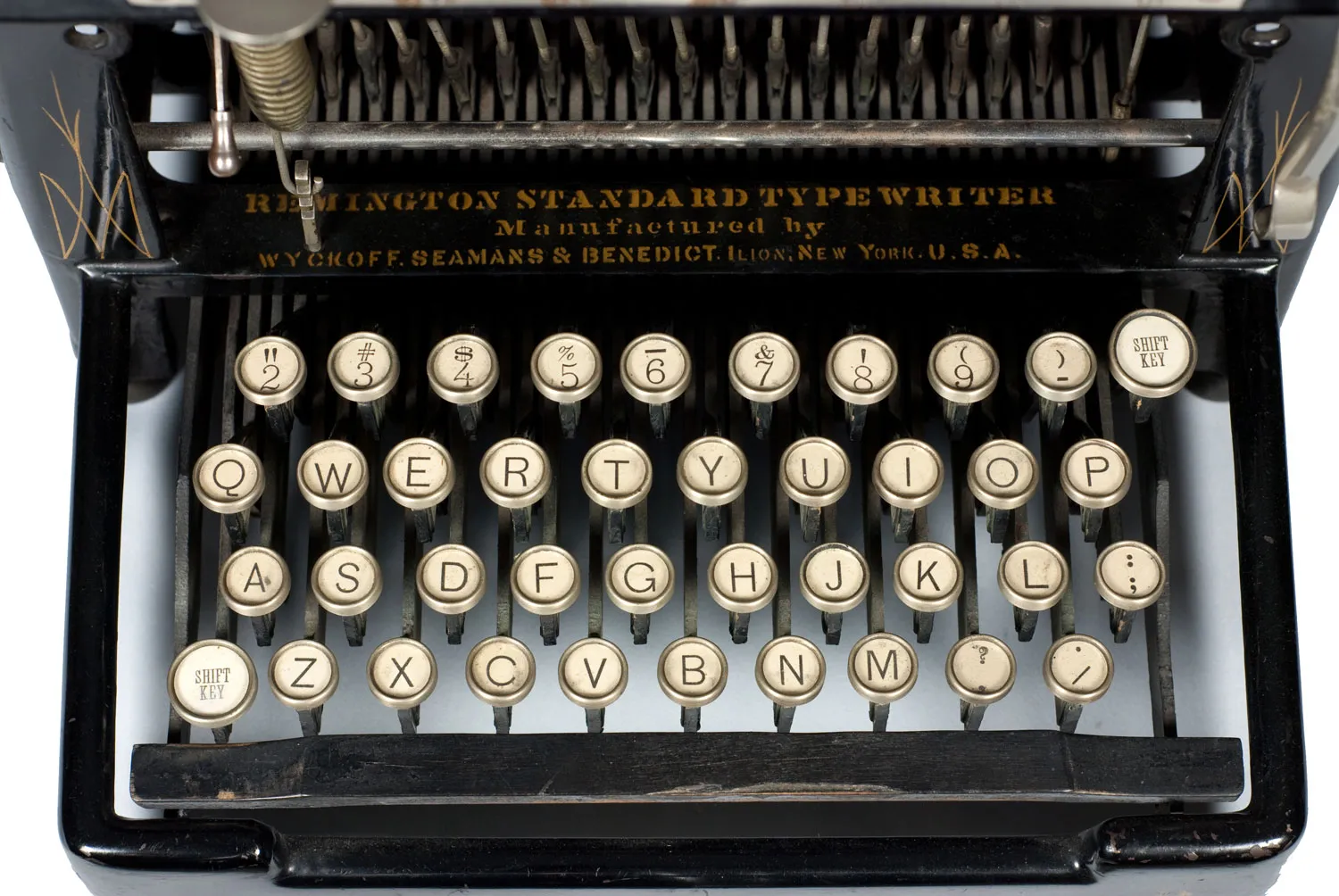 Close-up of a Remington Standard typewriter keyboard with round glass-topped keys in four rows, the second row reading Q W E R T Y U I O P and two keys marked shift key