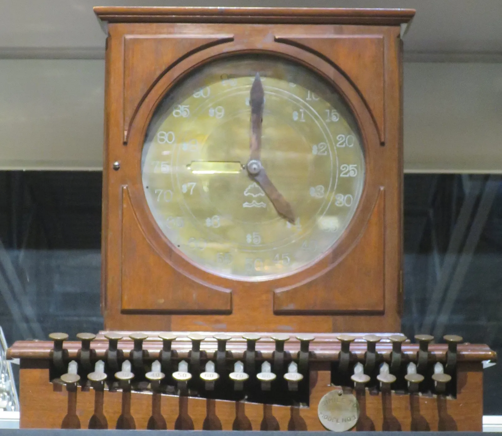 A reproduction of the Ritty Dial cash register, a wooden cabinet topped by a large clock-like dial for showing the sale amount