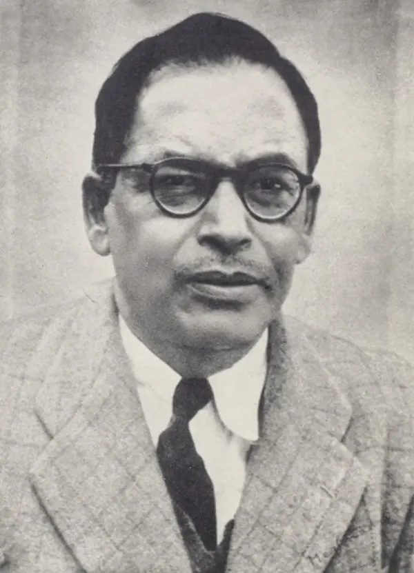 Black and white portrait of the astrophysicist Meghnad Saha in round dark-framed glasses, a checked jacket, white shirt and dark tie